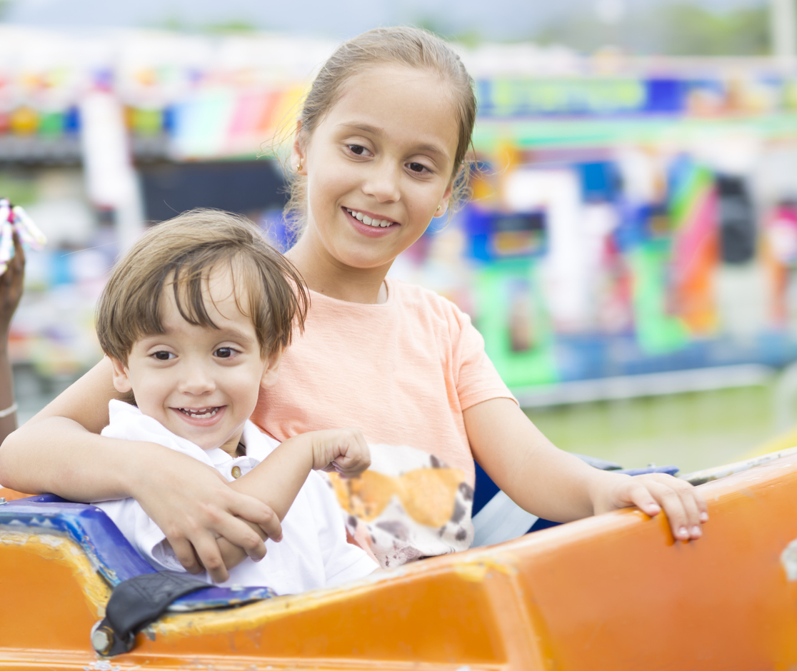 Girl and her little brother on an amusement ride having fun.