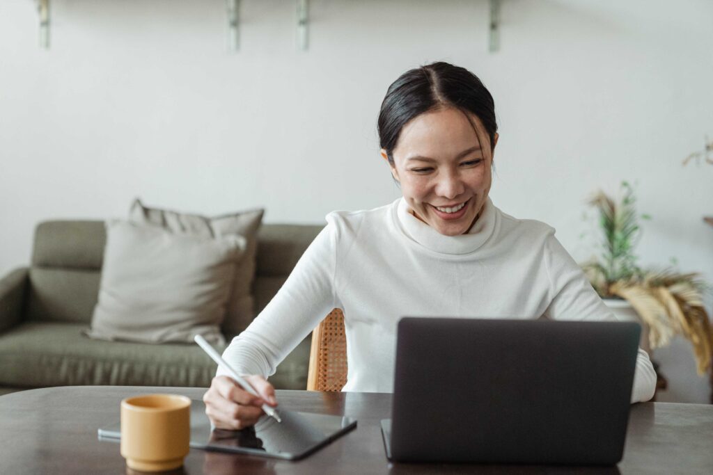 Woman sitting having a videocall and taking notes